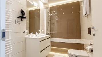 A modern bathroom with a glass-enclosed shower, a white sink, and a toilet.