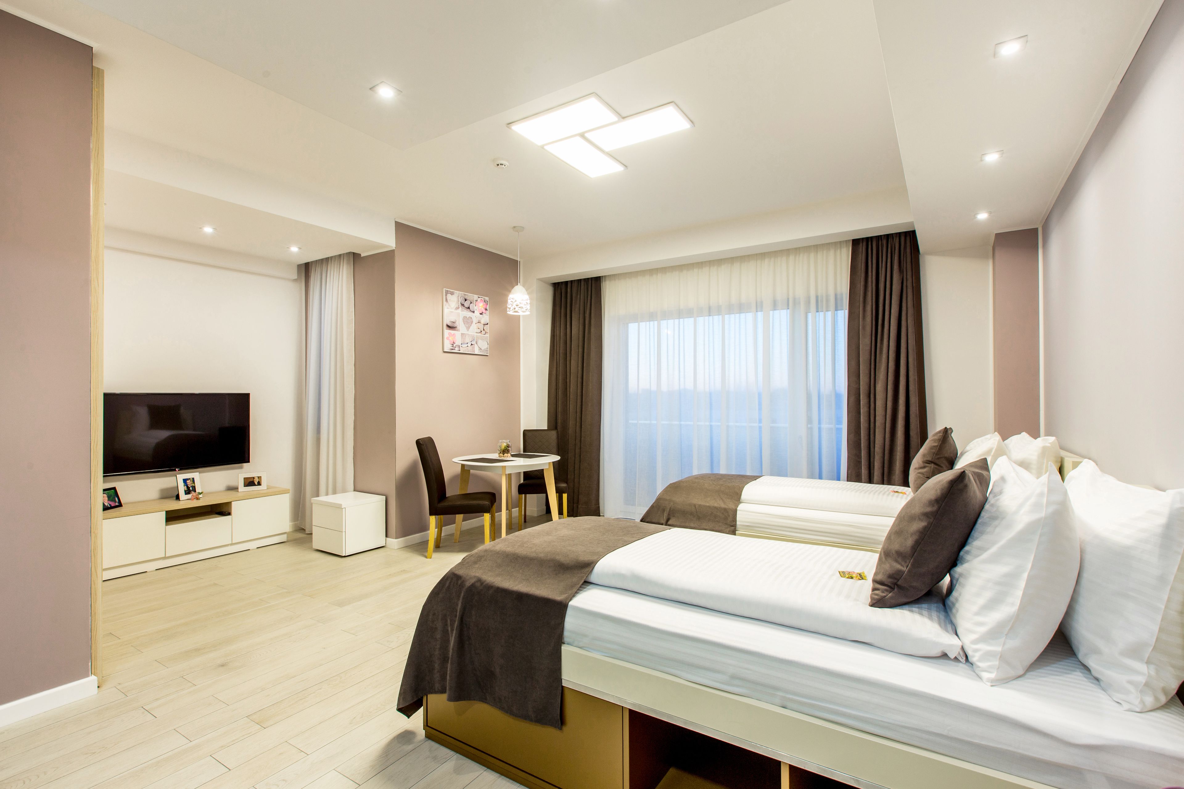Una habitación de hotel moderna con una cama grande, televisión, escritorio y una silla.