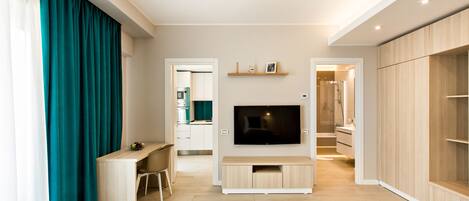 A modern living room with a flat-screen TV, wooden flooring, and a dining area with a table and chairs.