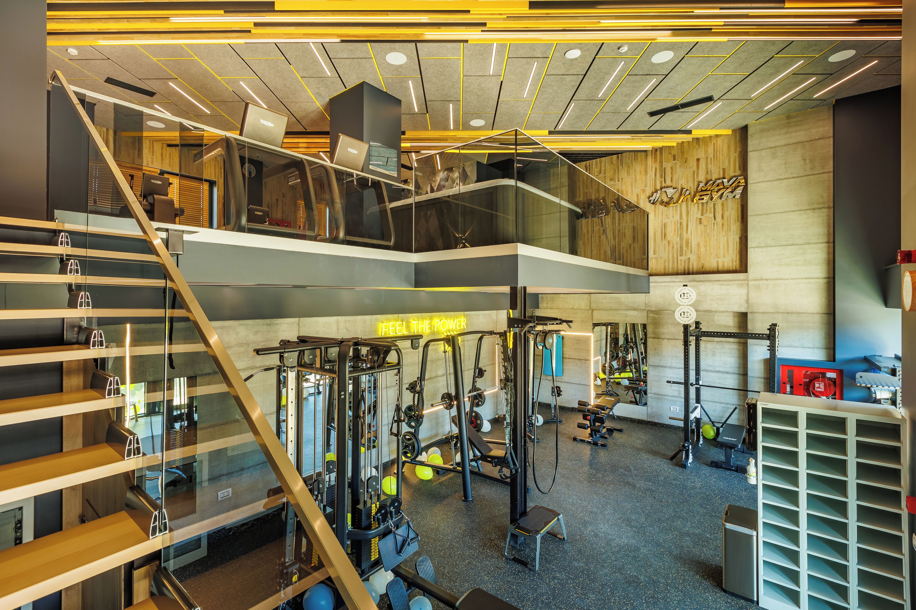 A multi-level gym with various exercise equipment, a staircase, and a motivational sign.