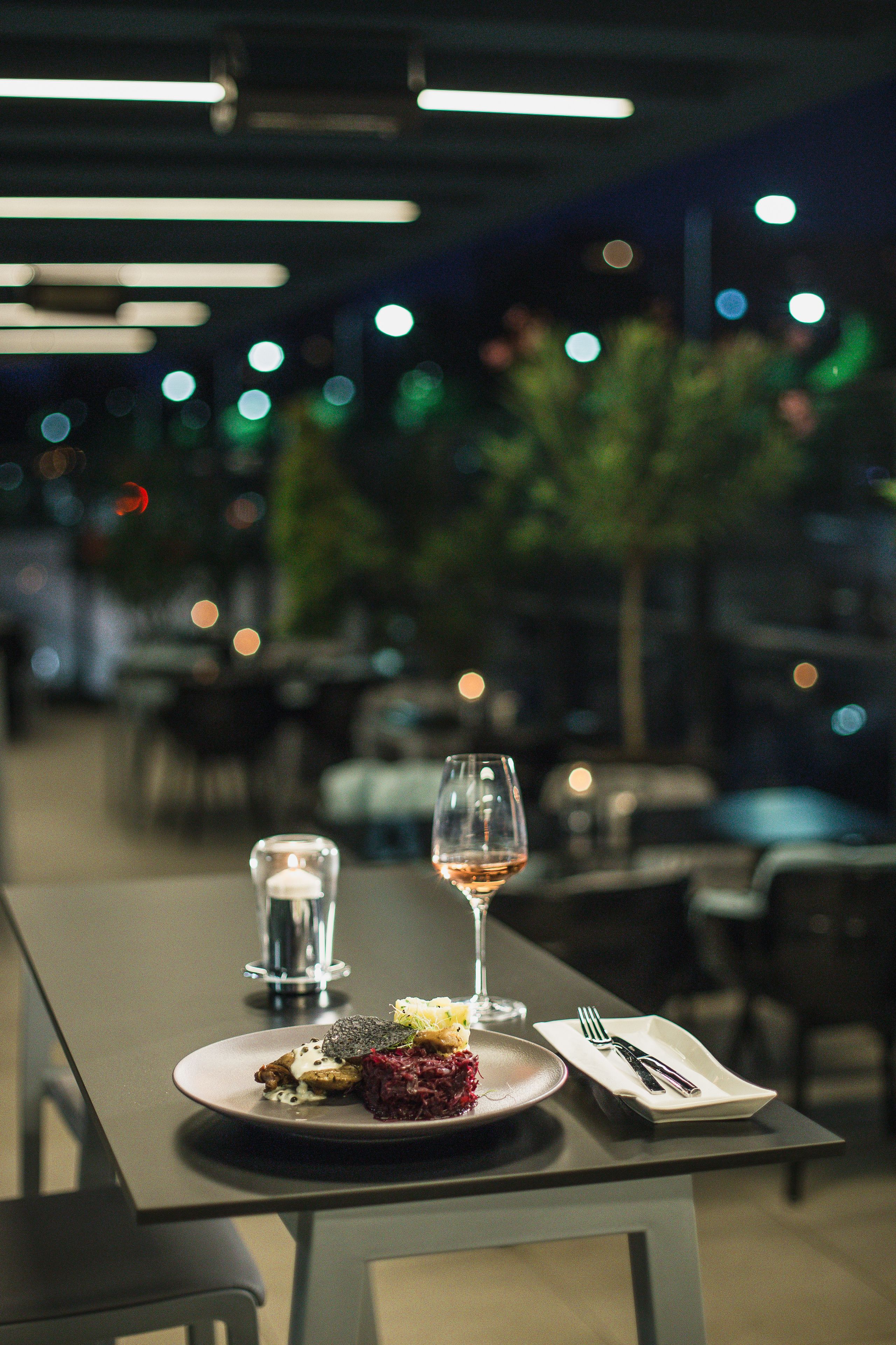 A dining table with a plate of food, a glass of wine, and cutlery.