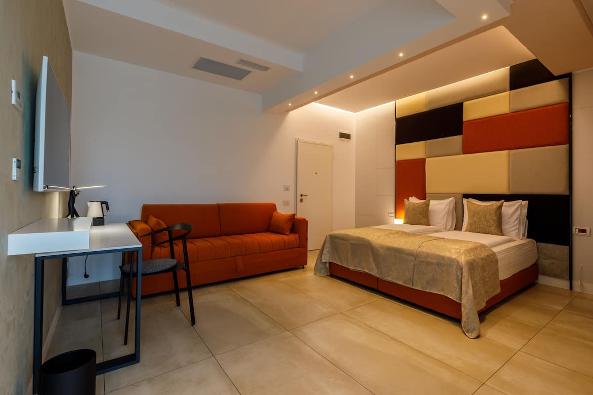A modern bedroom with a bed, a sofa, and a desk.