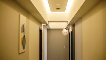 A modern hallway with a ceiling light, a number sign, and a framed artwork on the wall.