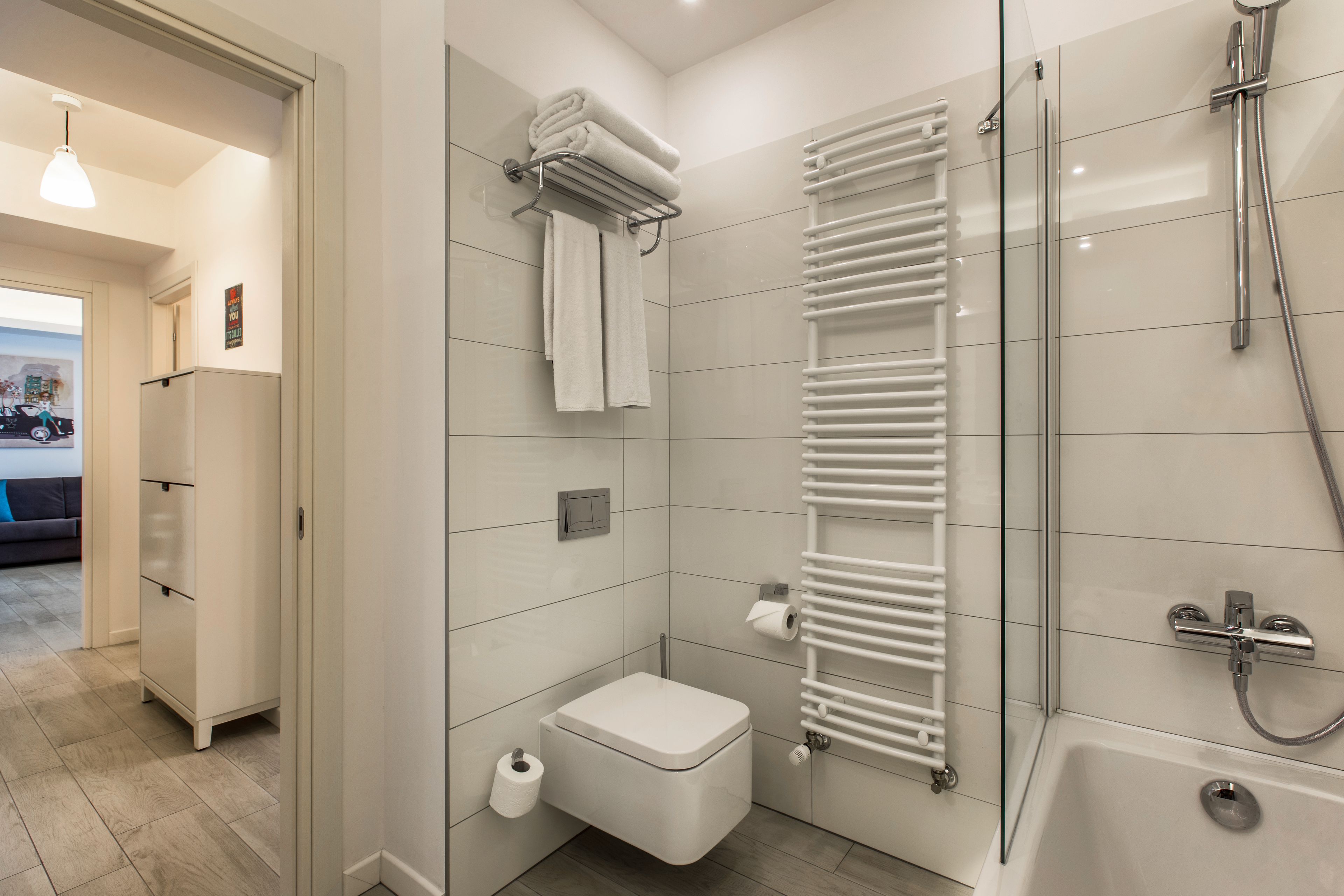 Un baño moderno con inodoro, cabina de ducha de vidrio y toallero blanco.