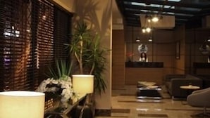 A modern interior with a glass ceiling, a reception desk, and a seating area with a coffee table. - Tuzla Town Hotel (Tuzla)