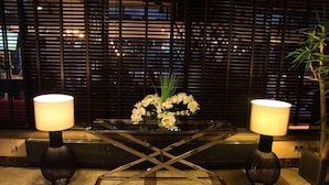 A modern lobby with a glass coffee table, two lamps, and a vase of flowers. - Tuzla Town Hotel (Tuzla)