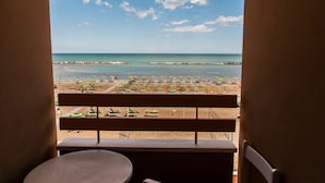 A balcony with a view of a beach, featuring umbrellas and a sandy shore. - Hotel Eden (Rimini)