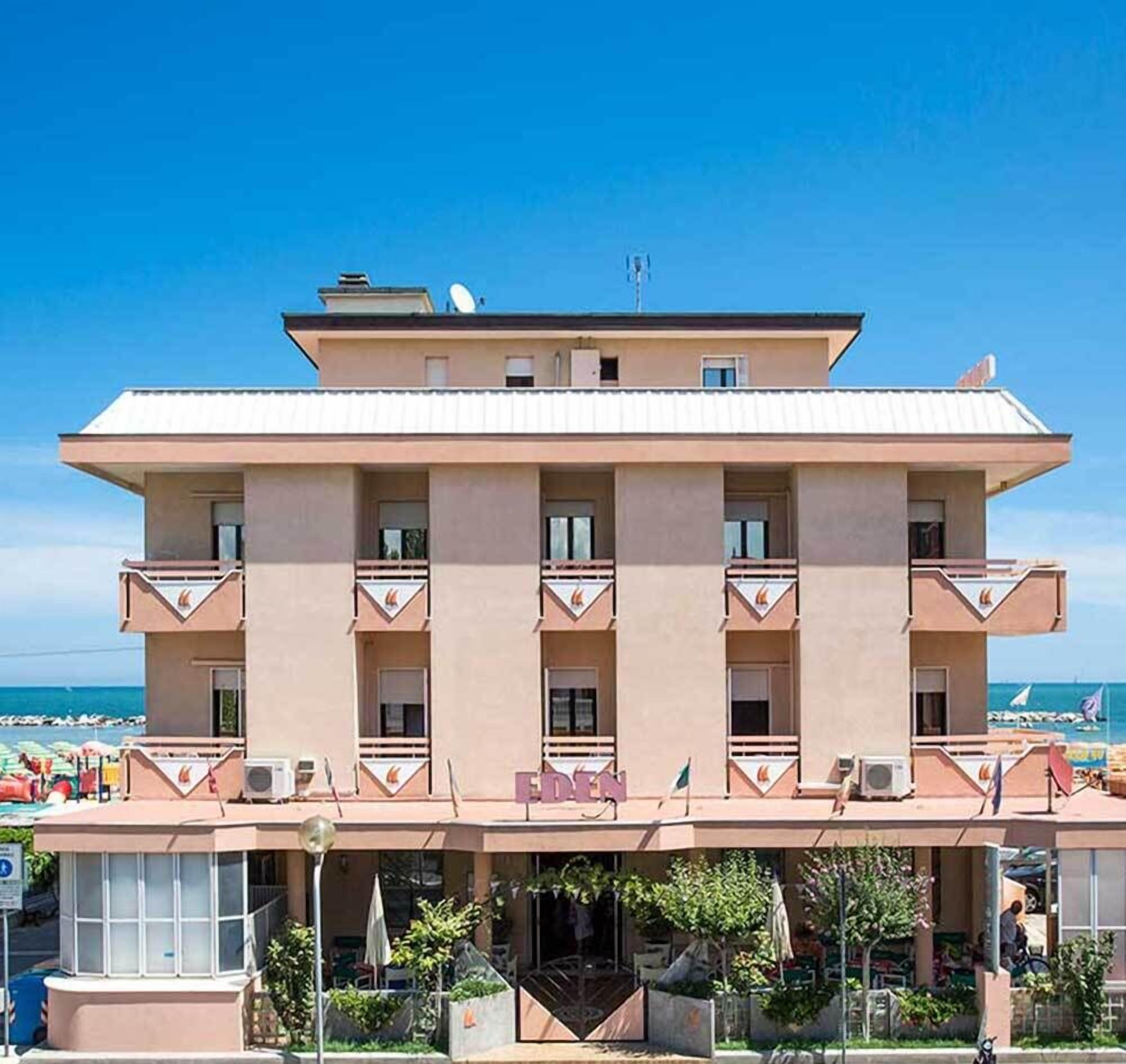 A multi-story hotel with a flat roof, balconies, and a beach view.