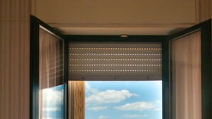 A hotel room with a bed, a view of the beach, and a balcony with a railing. - Hotel Eden (Rimini)