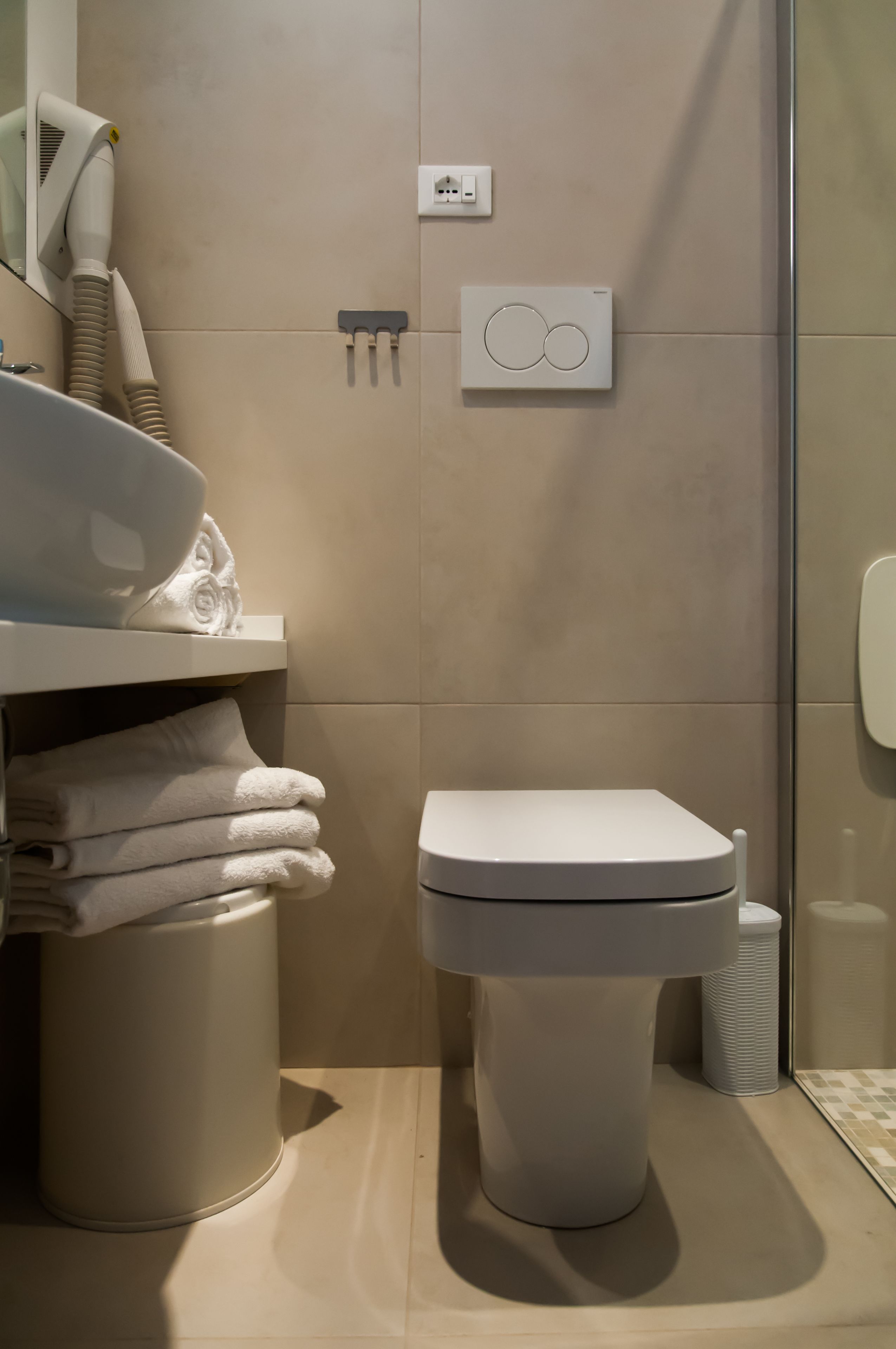 A modern bathroom with a toilet, a sink with a mirror, and a towel rack.