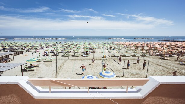 A beach with numerous umbrellas and sun loungers, a clear sky, and a view of the sea. - Hotel Eden (Rimini)