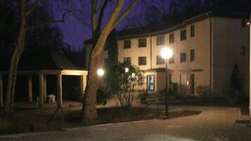 Um pátio com área de estar coberta, um edifício com várias janelas e um poste de luz.