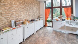 Eine moderne Küche mit Backsteinwand, weißen Schränken und einem großen Fenster mit orangefarbenen Vorhängen.