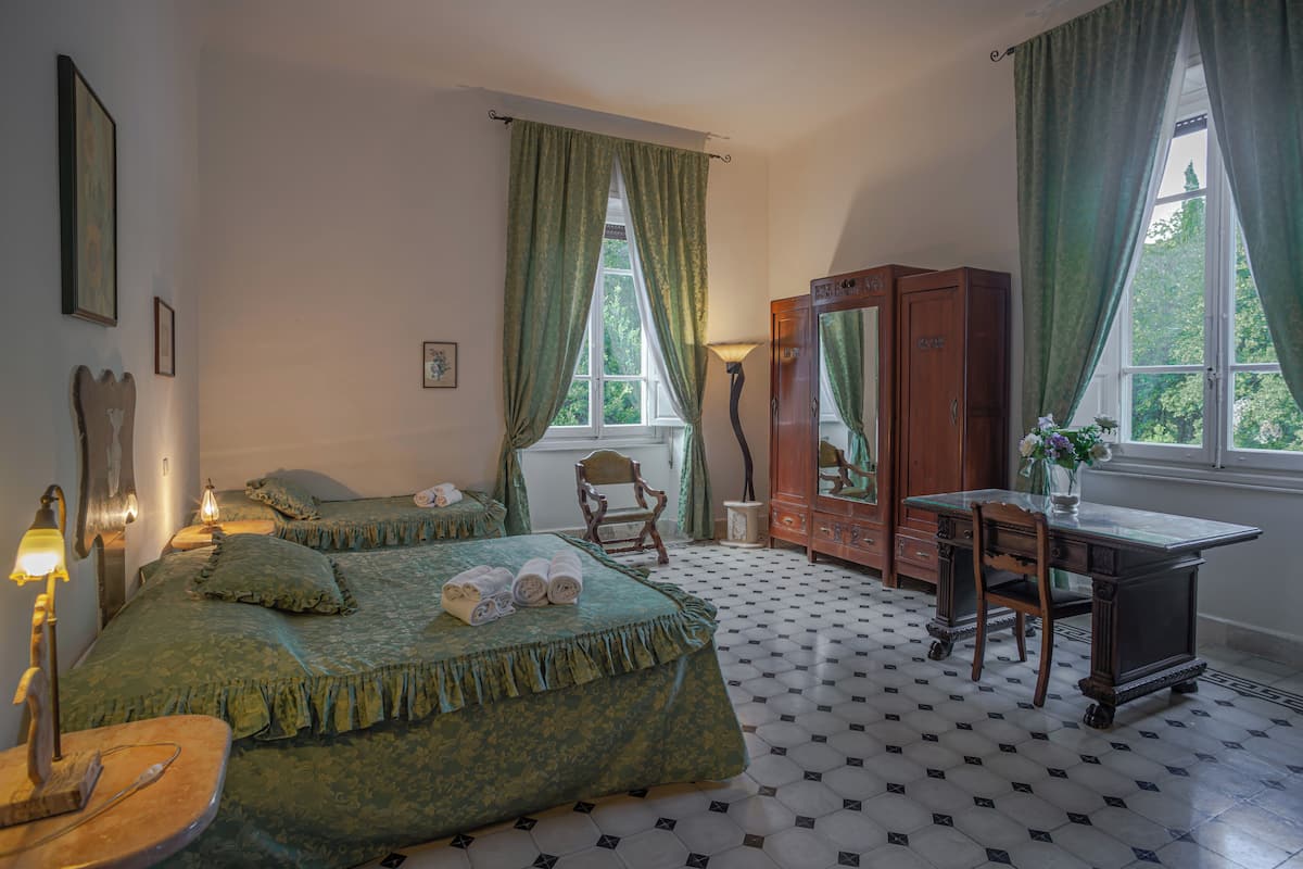 Quarto com cama, escrivaninha, cadeira, guarda-roupa e janela com cortinas.