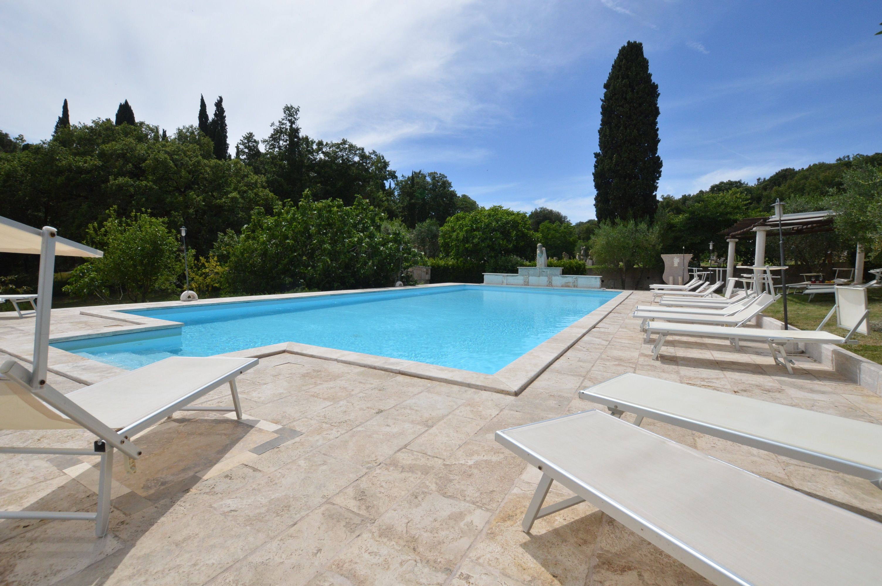 Une piscine avec des chaises longues et une pergola.