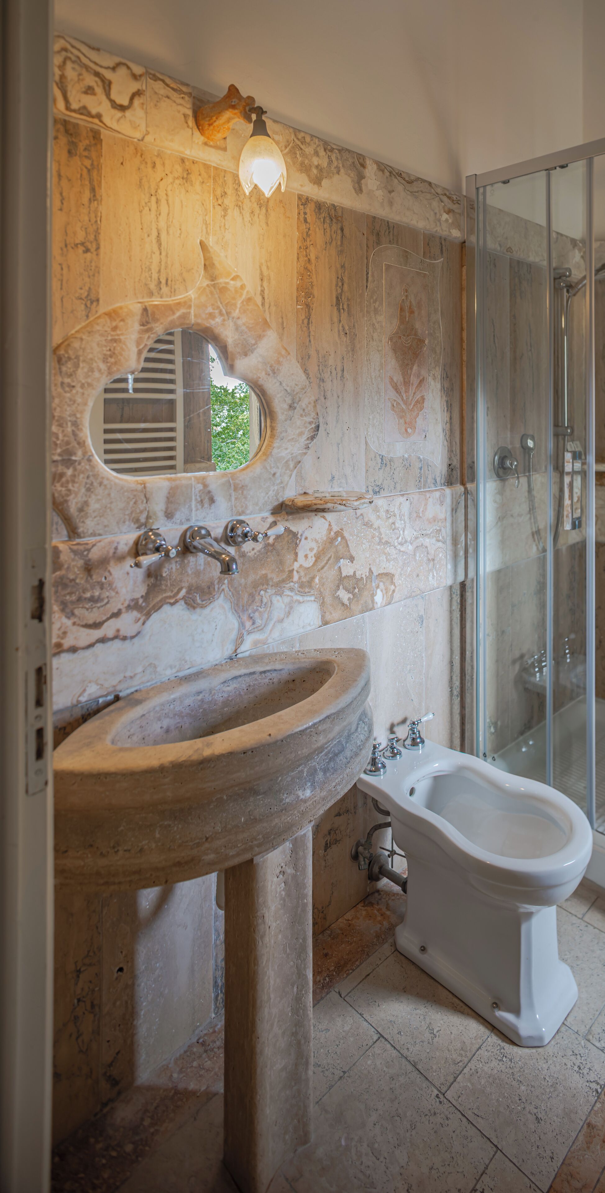 Un bagno con lavabo in pietra, un bidet e cabina doccia in vetro.