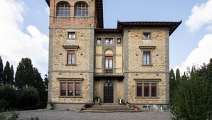 A two-story stone building with a central entrance, symmetrical windows, and a small balcony.