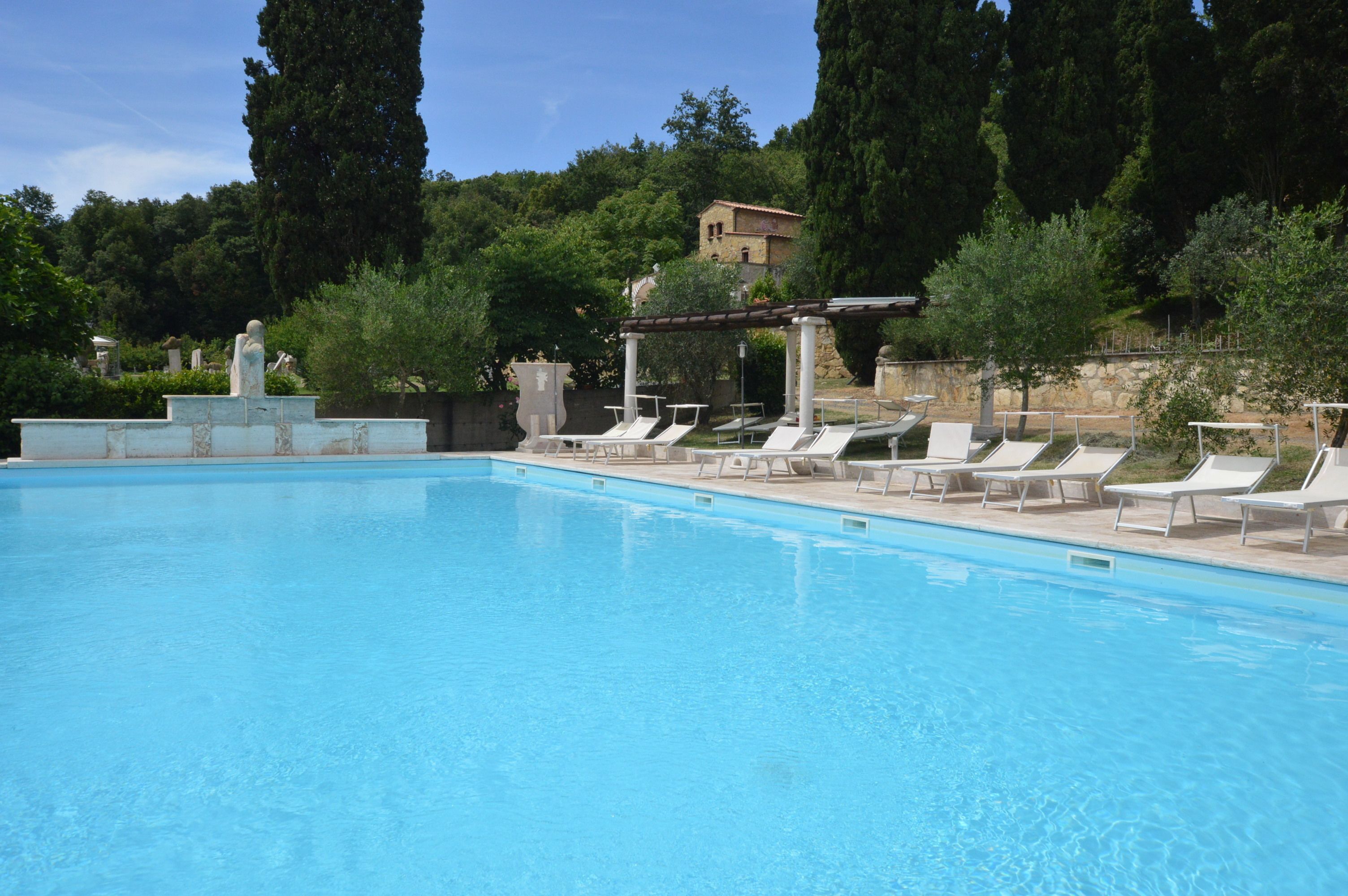 Une piscine avec des chaises longues et une pergola.