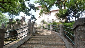 A stone staircase with metal railings leading to a building with a tiled roof.