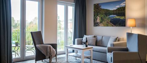 Een moderne woonkamer met een bank, fauteuils, een salontafel en een landschapsschilderij.