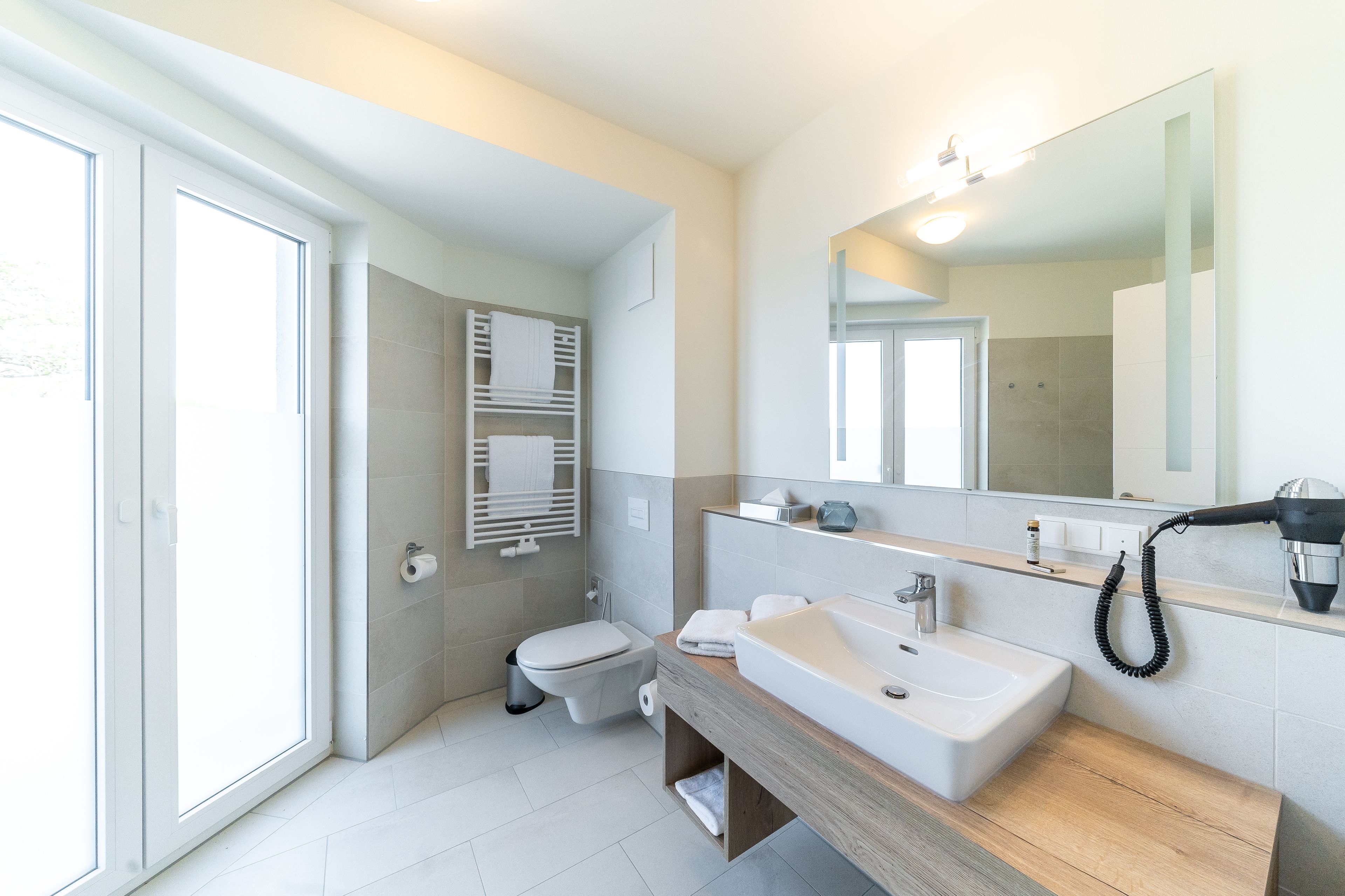 A modern bathroom with a toilet, bidet, sink, and mirror.