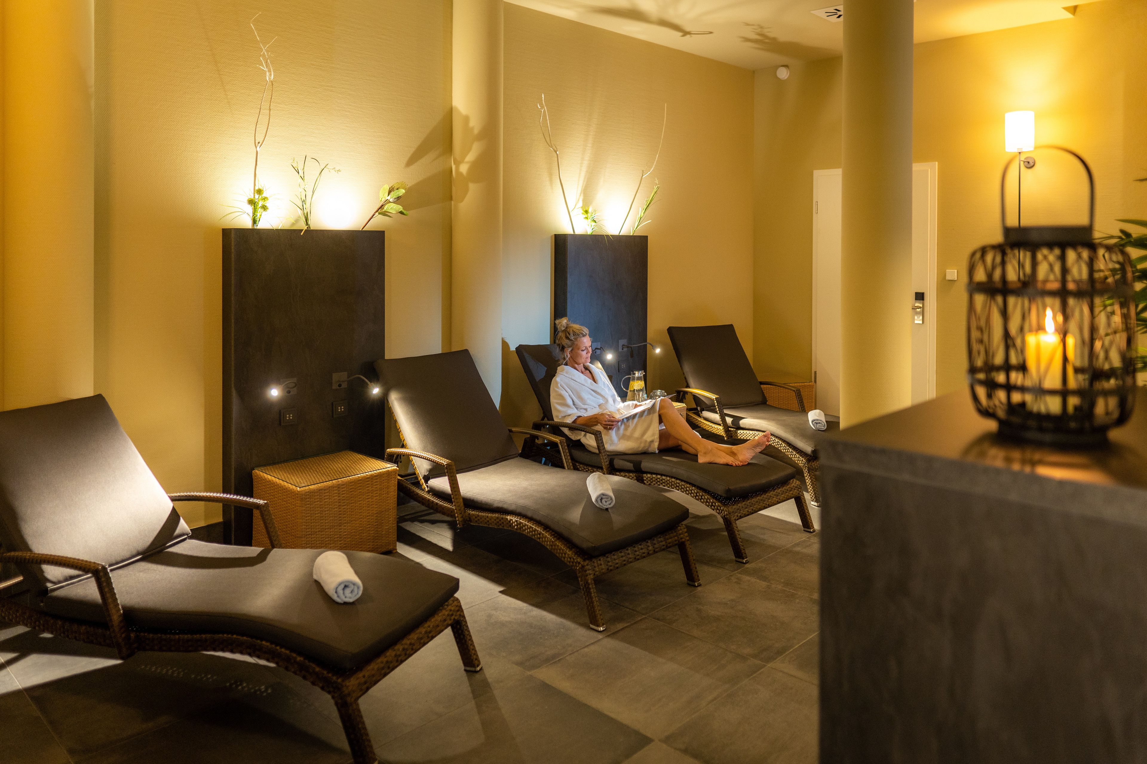Un área de spa con sillones reclinables, una recepción y una planta en la pared.