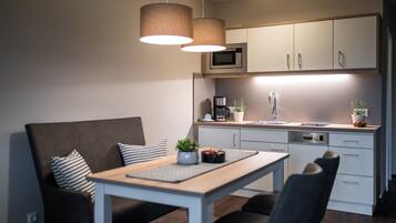 A modern kitchen with a dining area, featuring a microwave, coffee maker, sink, and cabinets.
