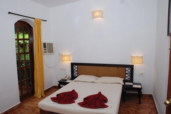 A hotel room with a bed, two bedside lamps, a telephone, and a window with a curtain. - Sea Breeze Beach Resort Candolim (Candolim)