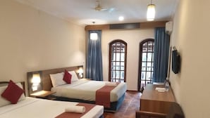 A hotel room with two beds, a desk, and a chair.
