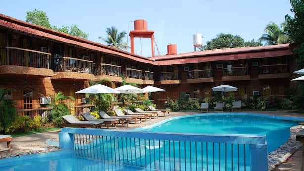 A hotel with a swimming pool, sun loungers, and umbrellas.