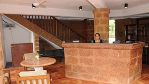 A lobby with a stone reception desk, a wooden staircase, and a round table with chairs.