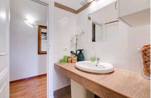 A bathroom with a wooden vanity, a white sink, and a mirror. - JD Rome (Rome)