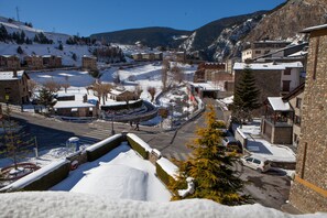 A snow-covered town with buildings, a road, and a mountain in the background.
