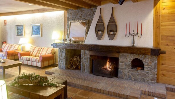 Una sala de estar acogedora con chimenea de piedra, vigas de madera y un sofá cómodo.