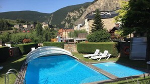 Una piscina con dos zonas, rodeada de un césped cuidado y algunas tumbonas.