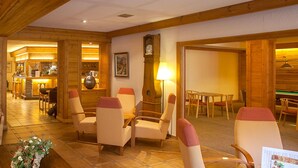 Un vestíbulo con zona de bar, disposición de asientos y un reloj en la pared.