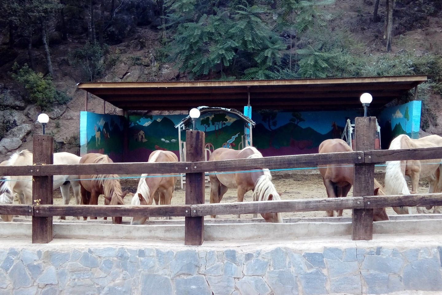 A stable with a roof and a mural in the background.
