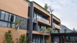 Un hotel moderno con piscina, varios balcones y plantas tropicales.