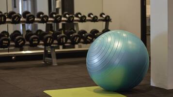 A gym with exercise equipment, including a blue exercise ball and dumbbells on racks.