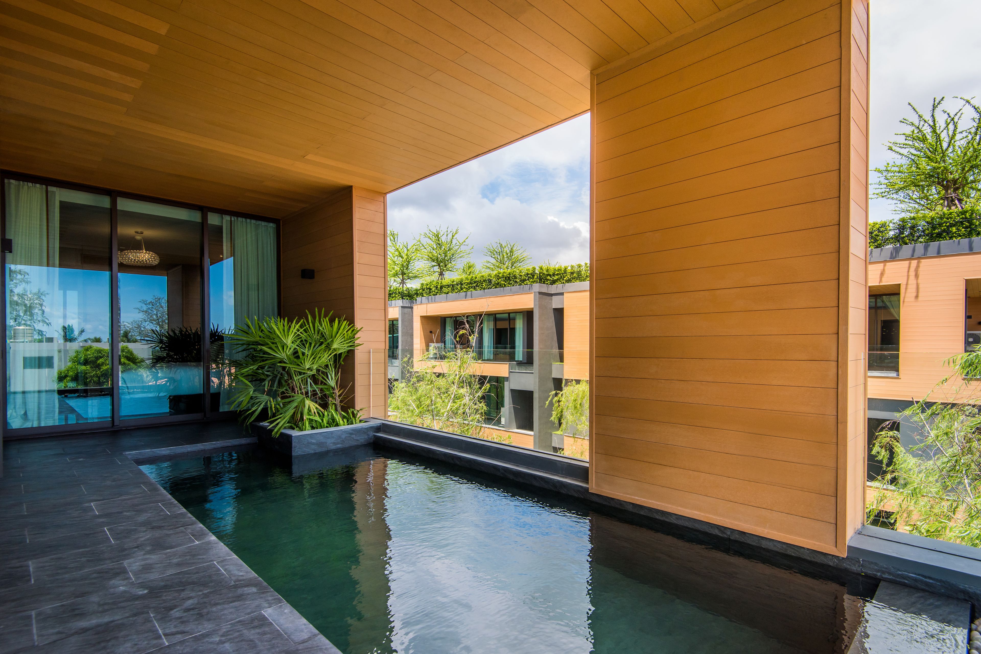 Ein moderner Poolbereich mit Holzboden, Glaswänden und Blick auf benachbarte Gebäude.