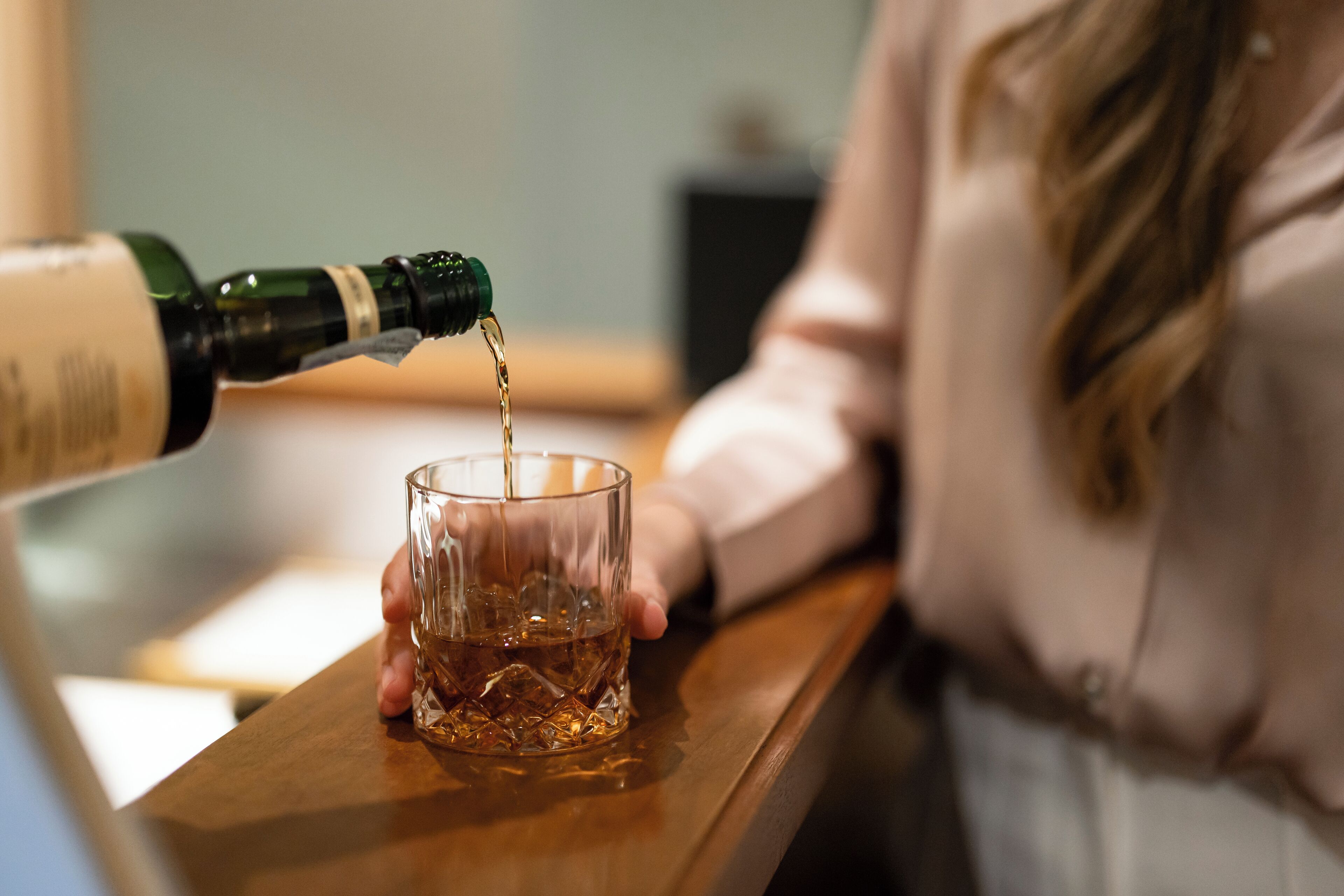 Une personne verse un liquide d’une bouteille dans un verre.