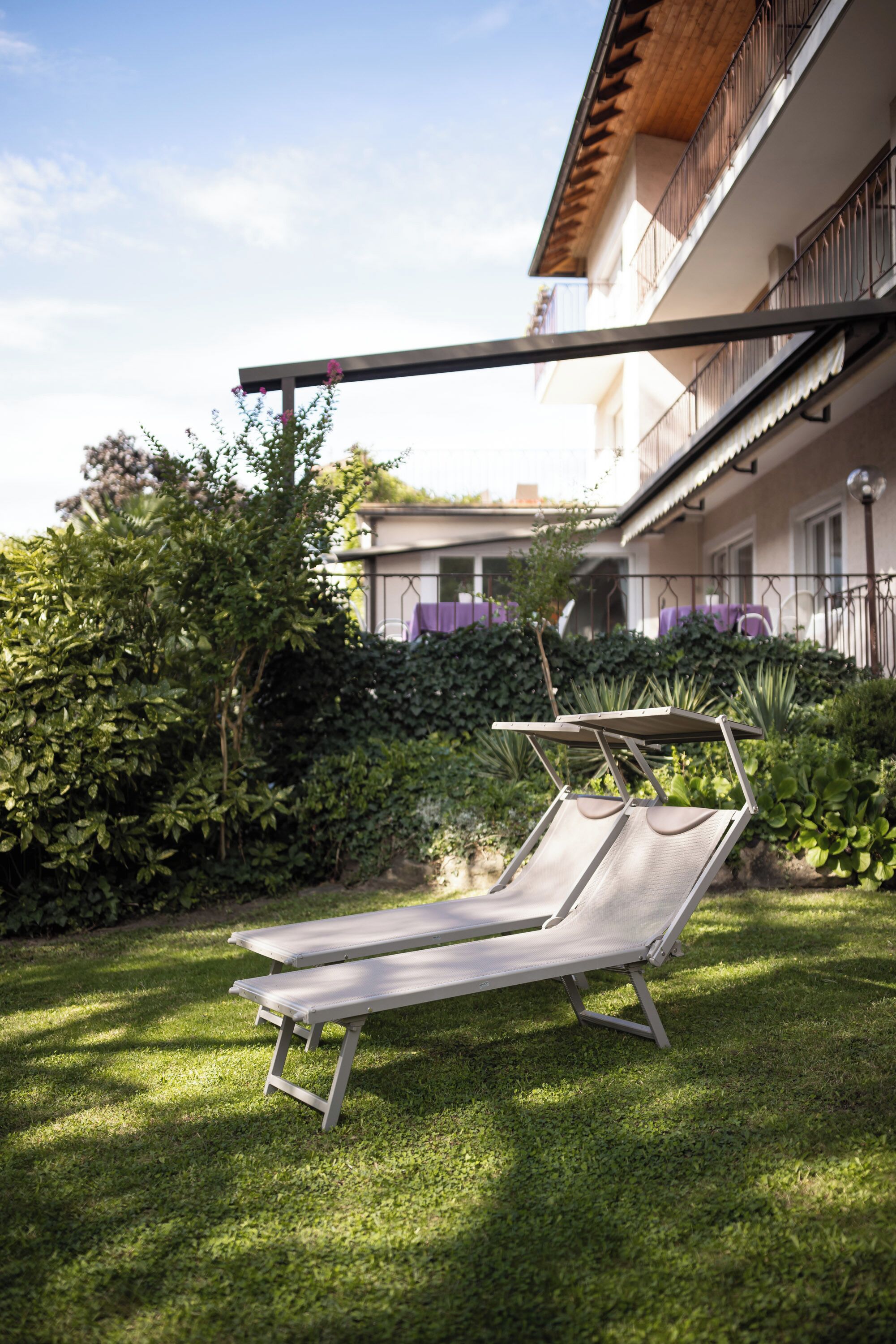 Un transat dans un jardin bien entretenu, avec un bâtiment en arrière-plan.
