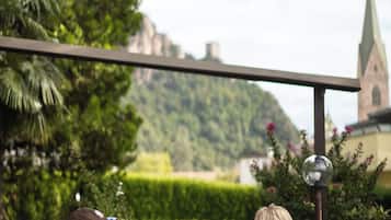 A couple dining at an outdoor table with a view of a church and hills in the background.