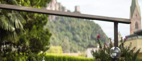 A couple dining at an outdoor table with a view of a church and hills in the background.