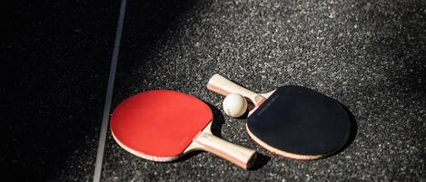 A table tennis table with two paddles and a ball.