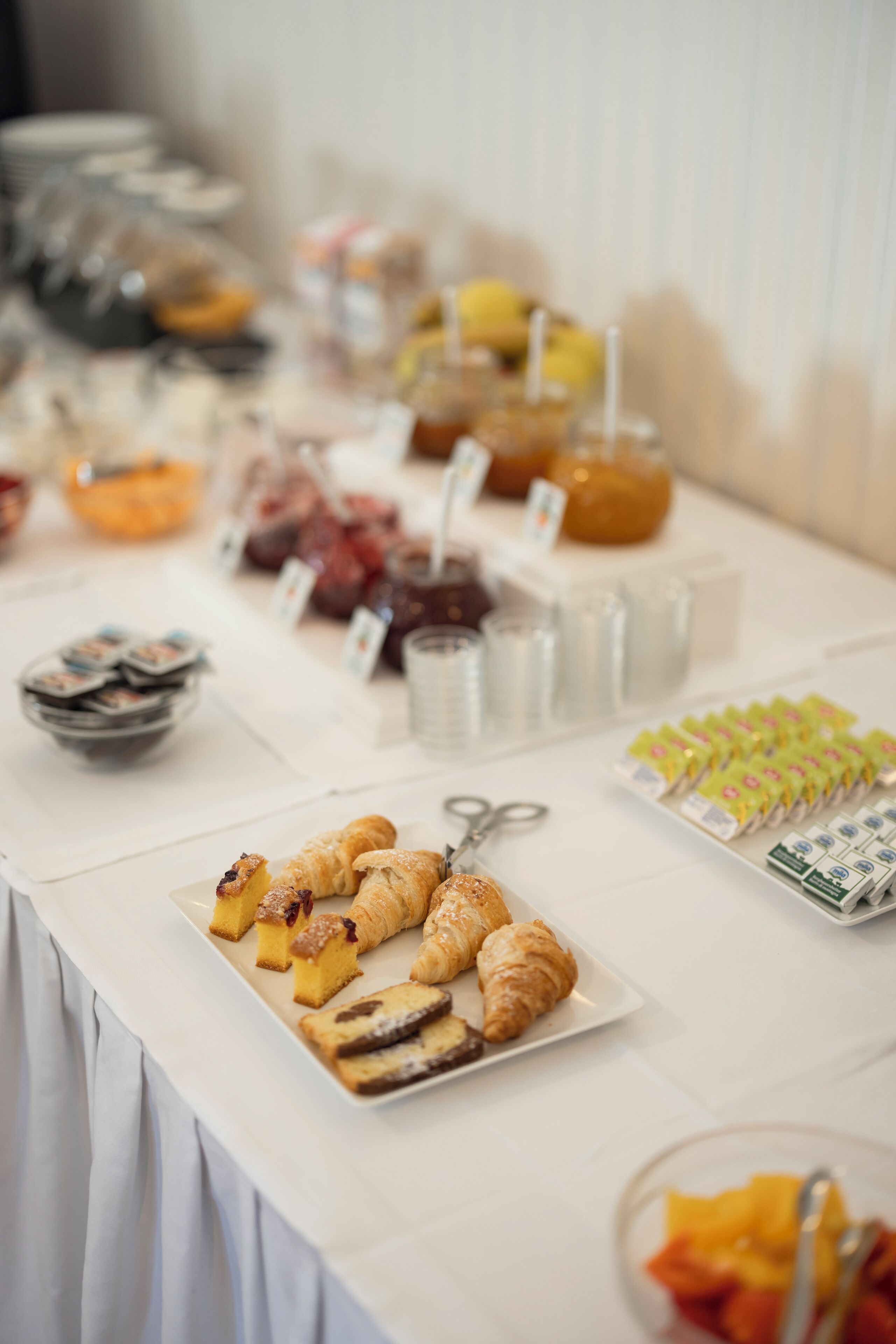A buffet table with various food items including pastries, fruits, and beverages.
