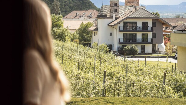 A view of a town with a church tower and a building with balconies. - Weingarten Terlan - Rooms & Breakfast (Terlano)
