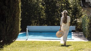 A person walking towards a swimming pool in a well-maintained garden area. - Weingarten Terlan - Rooms & Breakfast (Terlano)