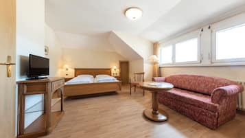 Ein Schlafzimmer mit einem Bett, einem Nachttisch, einem Fernseher und einem roten Sofa.