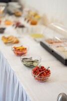 Uma mesa de buffet com diversos alimentos, incluindo frutas, legumes e carnes.
